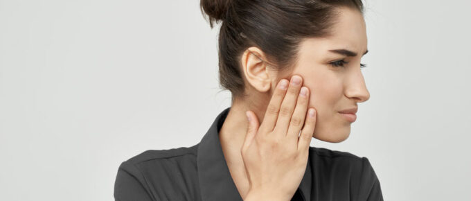 Patient applying heat therapy for jaw pain during treatment TMJ dysfunction in Tucson